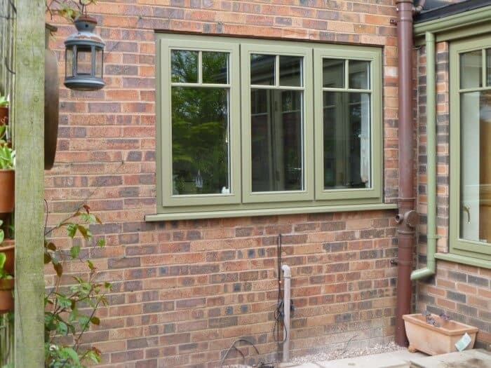 Green Accoya wood windows on brick house