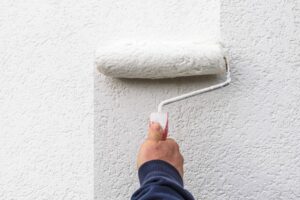 mans painting a wall with a roller brush