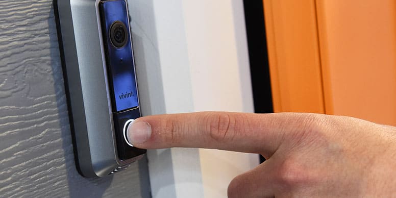 Close up of a smart camera door bell with a hand pushing the button